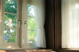 Abmontierter Fenstergriff mit sichtbaren Schrauben auf einem weißen Fensterrahmen