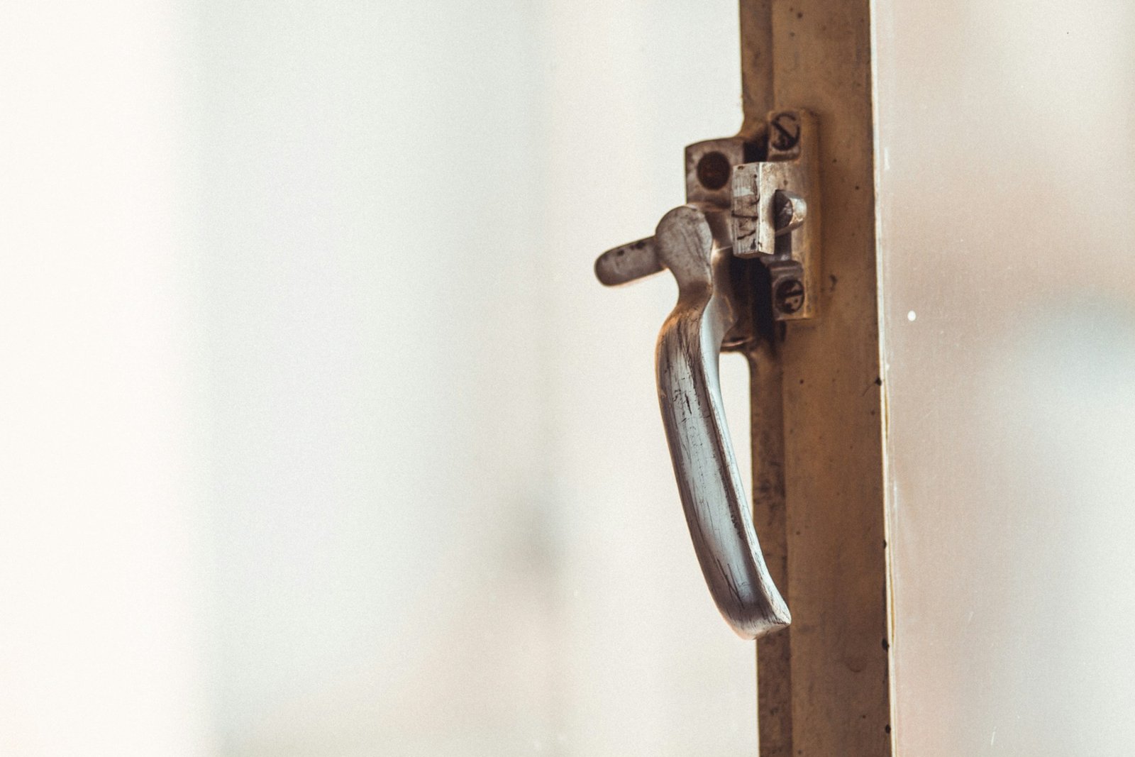 Hand dreht einen Fenstergriff, während das Fenster geschlossen bleibt