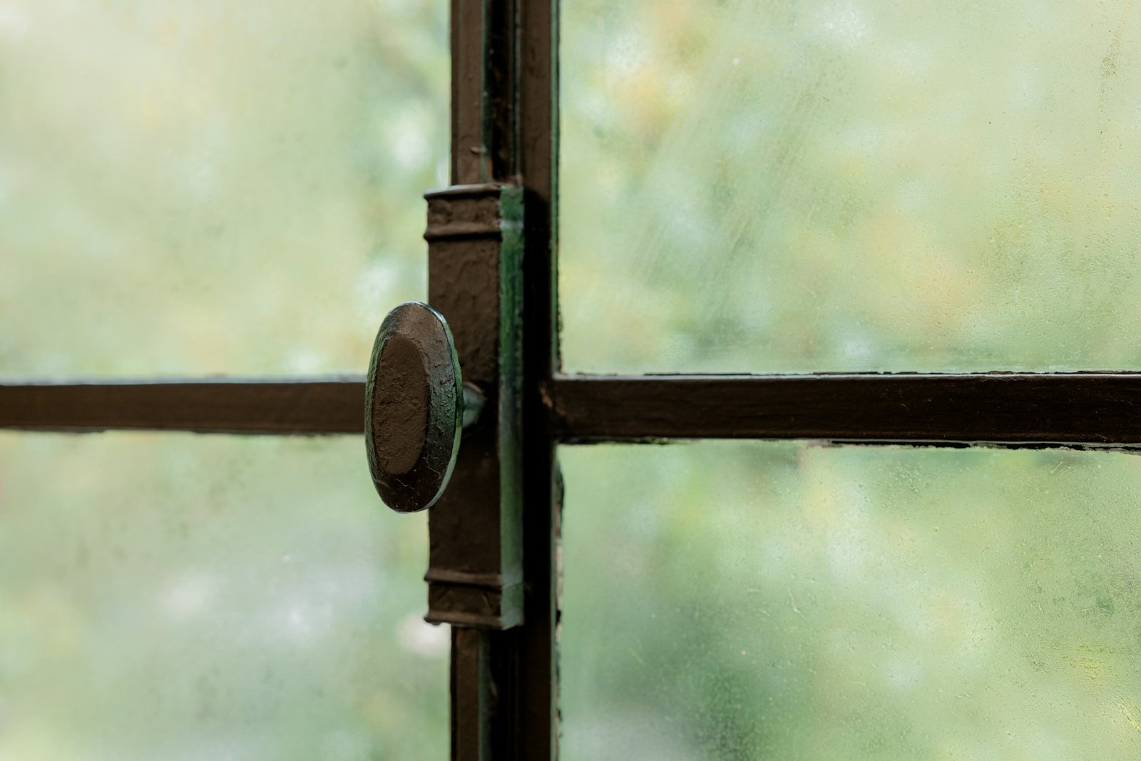 Abmontierter Fenstergriff liegt neben Schrauben auf einem Tisch