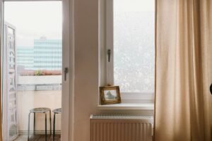 Metallischer Vierkantstift neben einem demontierten Fenstergriff auf weißem Untergrund